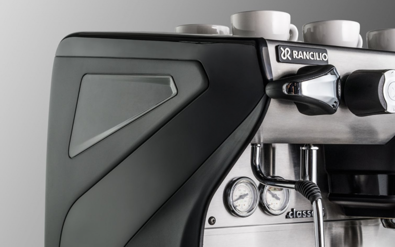 Closeup front-side view of the Rancilio Classe 5 espresso machine steam wand, steam c-lever, gauges and side panels. 